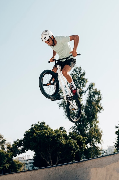 Joven extremo saltando con bicicleta vista de ángulo bajo