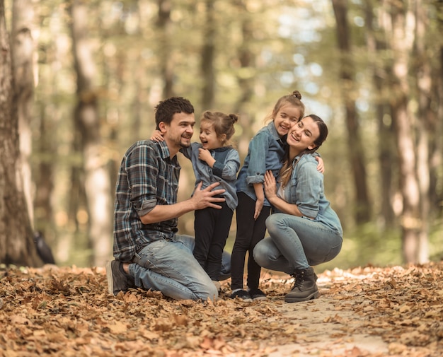 Una joven familia camina en el bosque de otoño con niños.