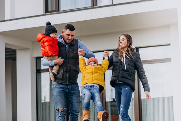 Joven familia con dos hermanitos junto a la casa