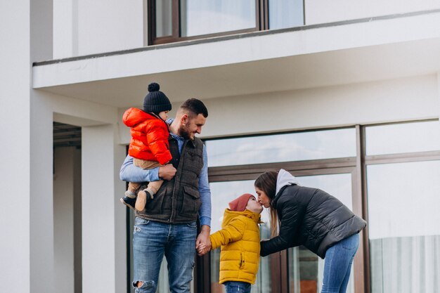 Joven familia con dos hermanitos junto a la casa