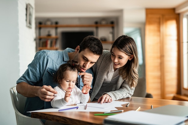 Joven familia feliz divirtiéndose mientras colorea el papel en casa