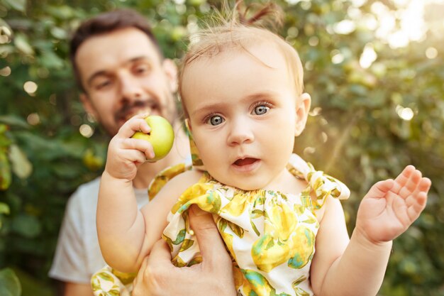 La joven familia feliz durante la recolección de manzanas en un jardín al aire libre