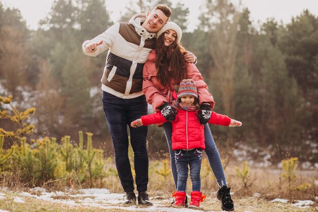 Joven familia juntos caminando en el bosque en invierno