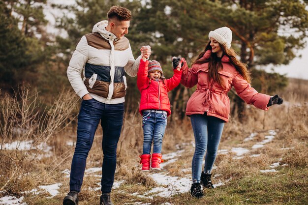 Joven familia juntos caminando en el bosque en invierno