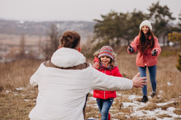 Joven familia juntos caminando en el bosque en invierno