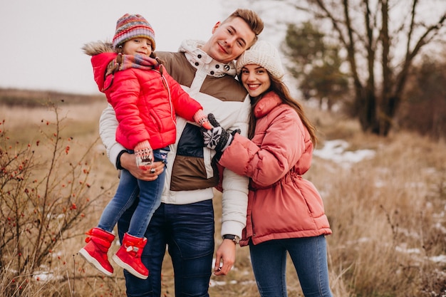 Joven familia juntos caminando en el bosque en invierno