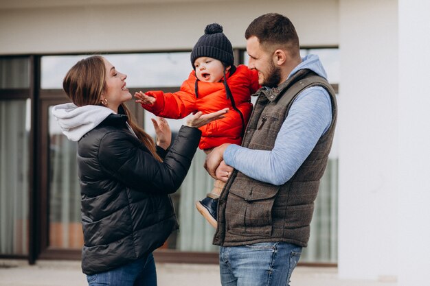 Joven familia con pequeño hijo junto a la casa