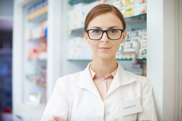 Joven farmacéutico de pie en la farmacia