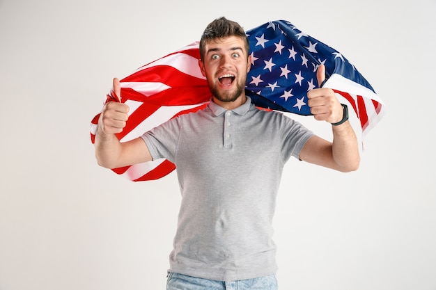 Foto gratuita joven feliz con la bandera de los estados unidos de américa aislado en blanco studio.