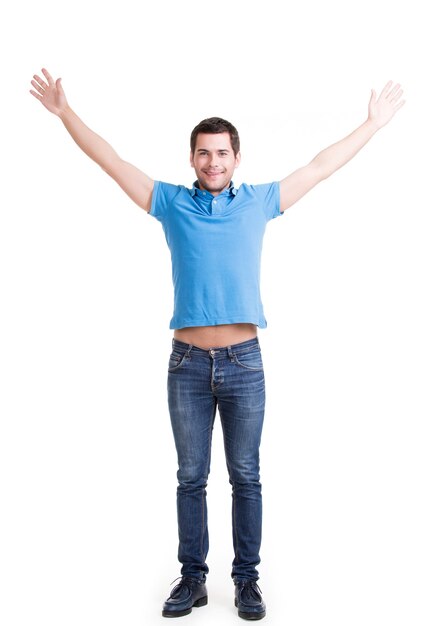 Joven feliz en casual con las manos levantadas aisladas en la pared blanca.