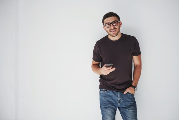 joven feliz casual vestido con teléfono inteligente en blanco