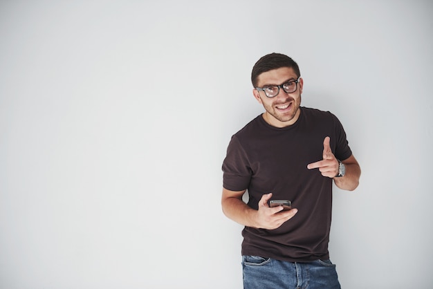 joven feliz casual vestido con teléfono inteligente en blanco