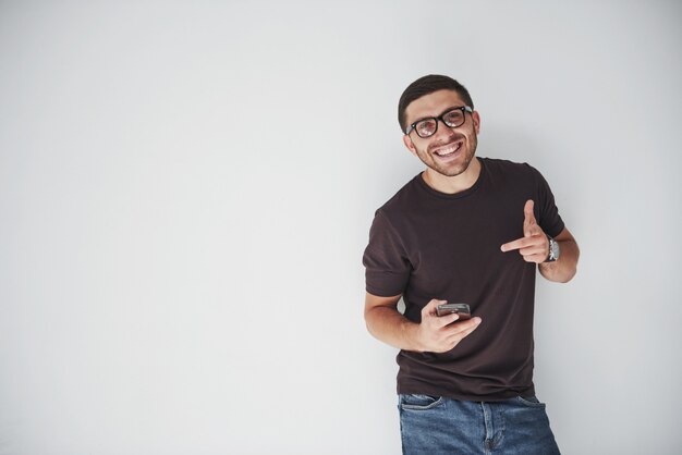 joven feliz casual vestido con teléfono inteligente en blanco