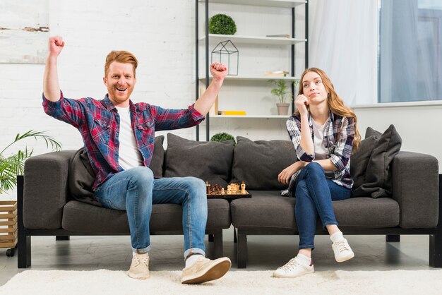 Joven feliz disfrutando del éxito después de jugar al ajedrez con su novia