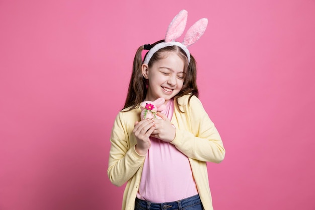 Foto gratuita una joven feliz y emocionada posando con un conejo de peluche en el estudio