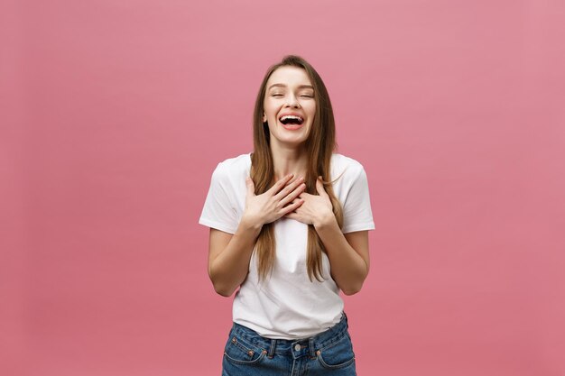 Una joven feliz y exitosa con una sonrisa, gritando y celebrando el éxito sobre un fondo rosa