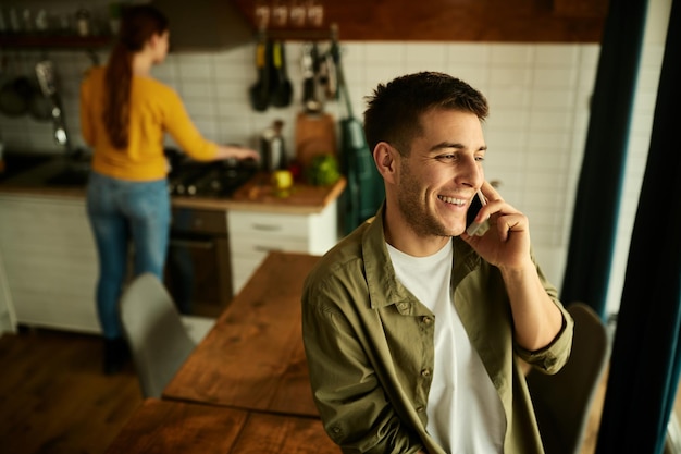 Joven feliz hablando por teléfono celular en casa