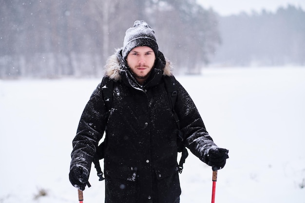 Joven feliz haciendo trekking junto al bosque nevado