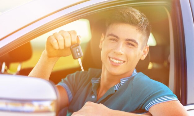 Joven feliz con llaves en auto sonriendo - concepto de comprar auto