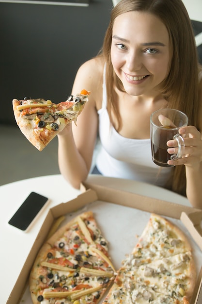 Joven feliz niña con una rebanada de pizza