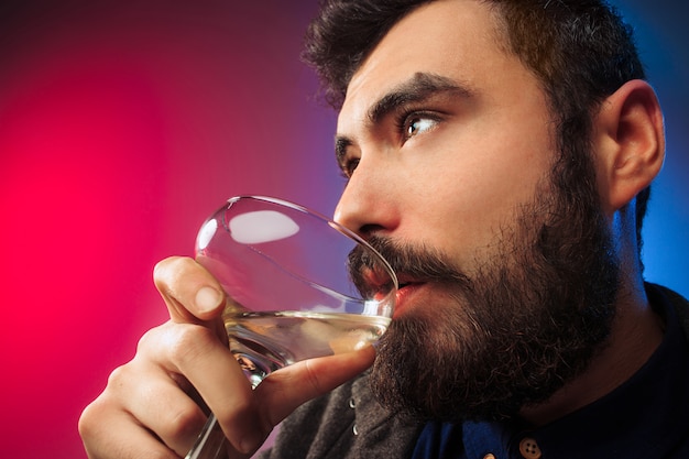 El joven feliz posando con una copa de vino.