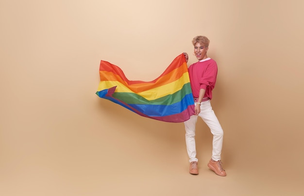 Foto gratuita joven feliz y sonriente asiático transgénero lgbt agitando la bandera del arco iris