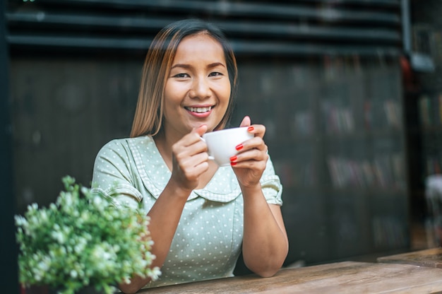 La joven felizmente bebe café en la cafetería