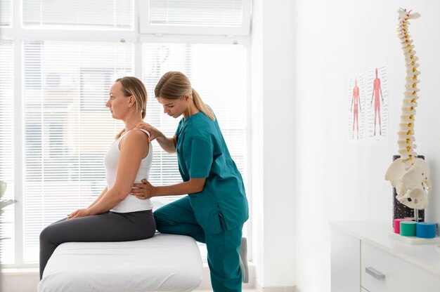 Joven fisioterapeuta ayudando a un paciente con problemas de espalda