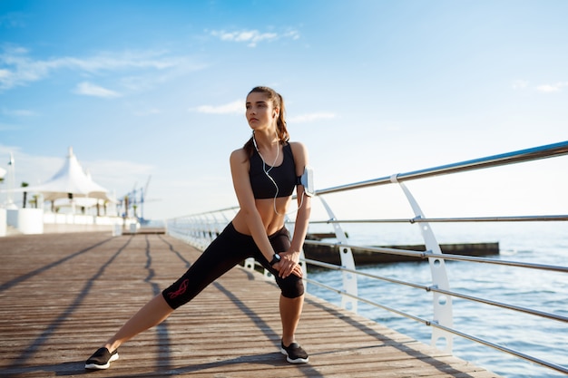 joven fitness girl que hace ejercicios deportivos con costa del mar en la pared