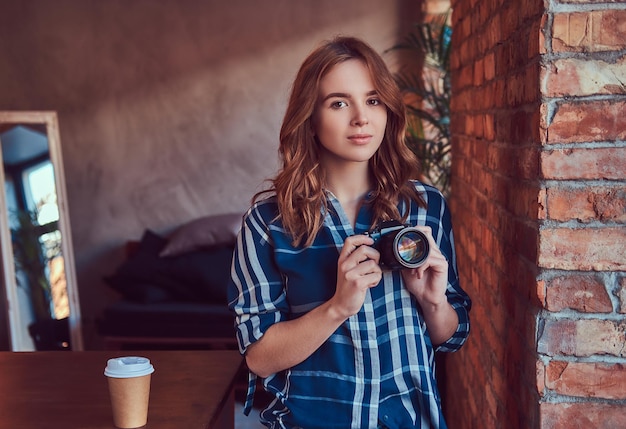 Foto gratuita joven fotógrafa encantadora se encuentra en una habitación con un loft en