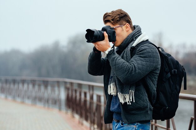 Joven fotógrafo con estilo tiene cámara profesional, tomar fotos.