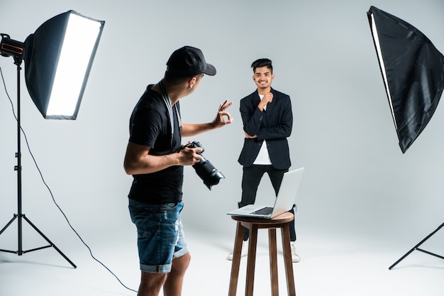 Foto gratuita joven fotógrafo profesional tomando fotos de modelo indio en estudio con leight