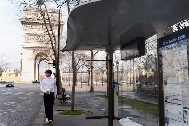 Joven francés esperando en la estación el autobús y bebiendo café