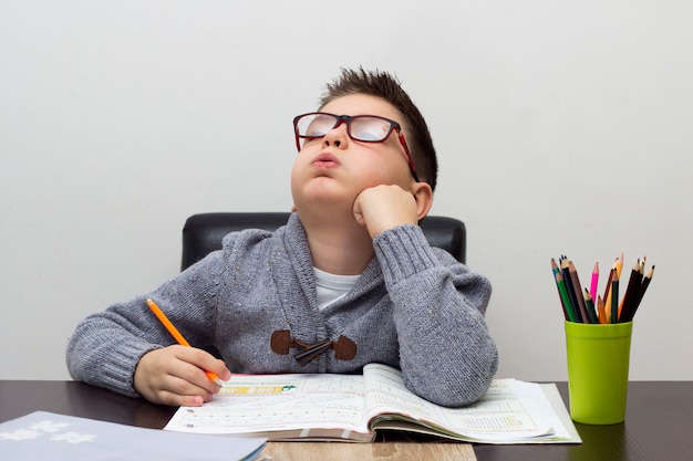 Foto gratuita joven frustrado sobre la tarea, escribiendo en casa. muchacho que estudia en la tabla. niño de dibujo con un lápiz.