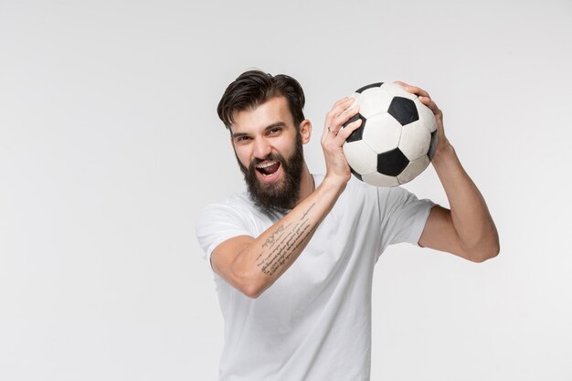 Joven futbolista con balón delante de la pared blanca