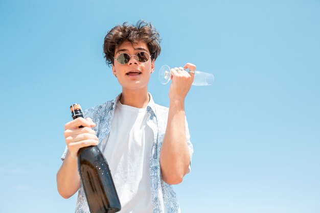 Joven con gafas de sol y botella de champagne