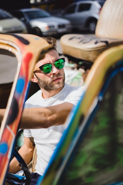 joven en gafas de sol en un cabriolet