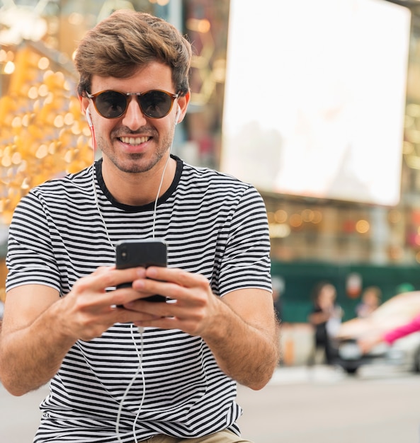 Foto gratuita joven con gafas de sol escribiendo smartphone