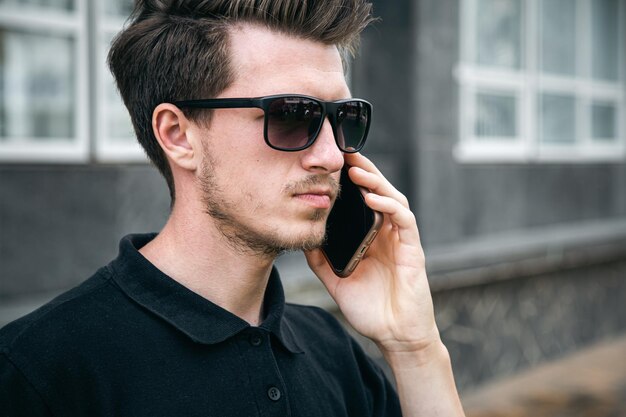 Un joven con gafas de sol está hablando por un teléfono inteligente