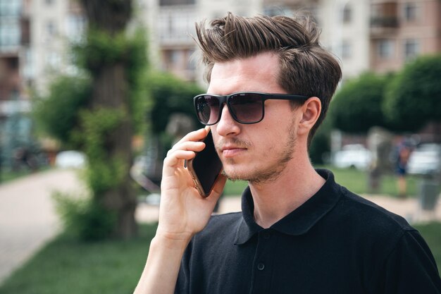 Un joven con gafas de sol en verano en el primer plano de la ciudad