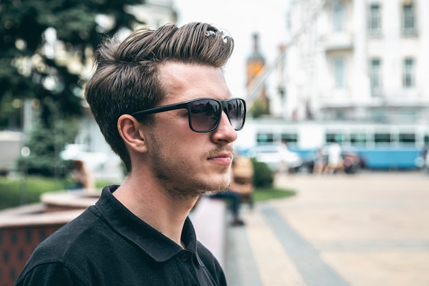 Un joven con gafas de sol en verano en el primer plano de la ciudad