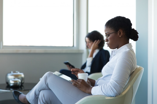 Joven gerente mujer leyendo noticias en tableta