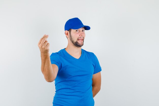 Joven gesticulando con los dedos en camiseta azul y gorra