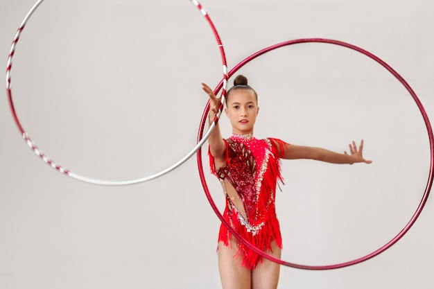 Joven gimnasta entrenando en el gimnasio con aros de hula