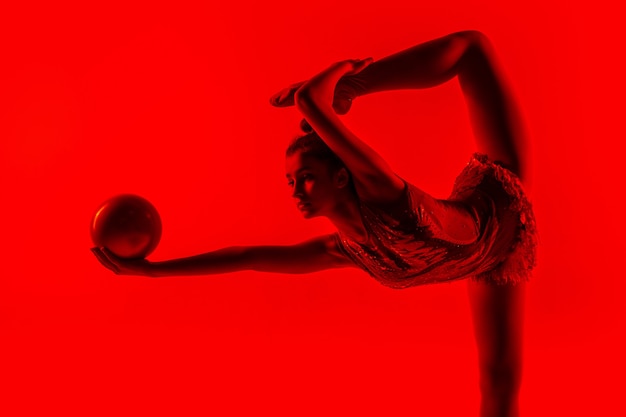 Foto gratuita joven gimnasta femenina flexible aislada en rojo