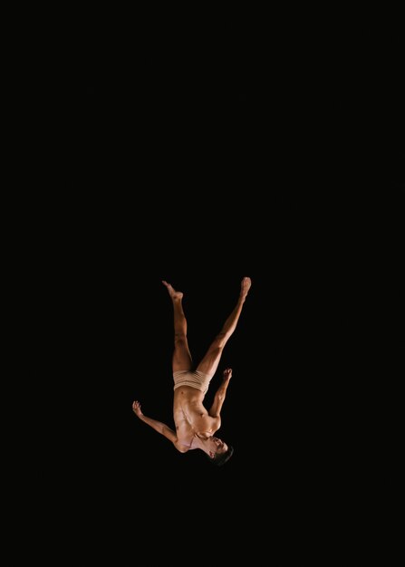 Joven gimnasta masculino volando boca abajo