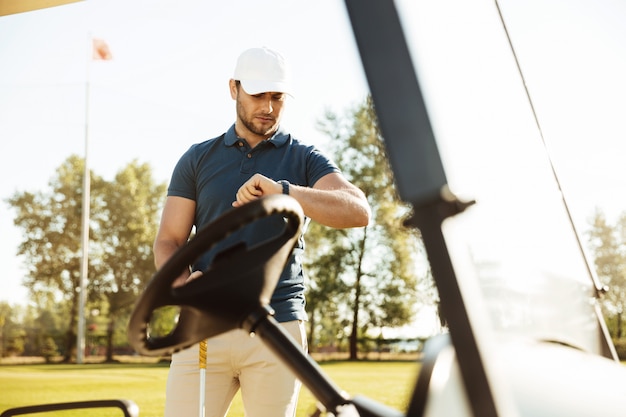 Foto gratuita joven golfista masculino mirando un reloj de pulsera