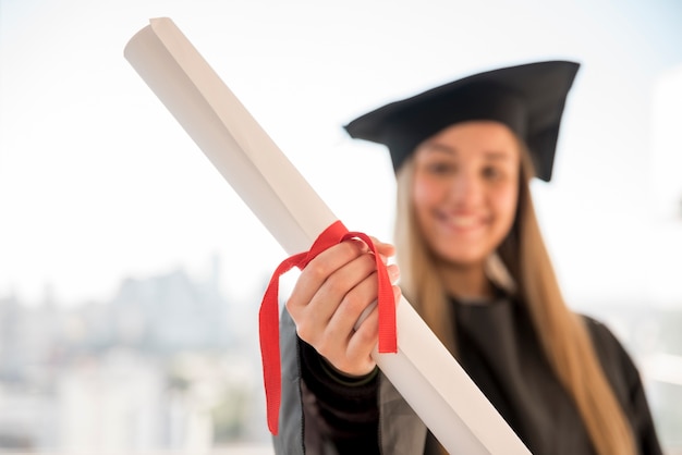 Foto gratuita joven graduada mostrando su certificado de primer plano