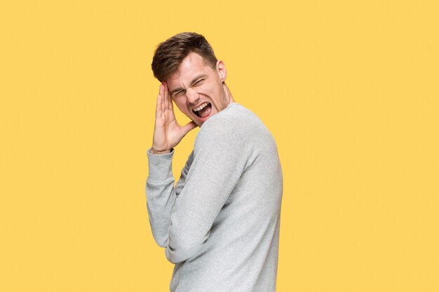 Joven gritando de alegría sobre fondo amarillo studio