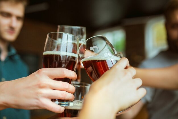 Joven grupo de amigos tintineando botellas de cerveza, divirtiéndose y celebrando juntos.